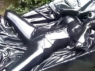 Latex girl full in black rubber and Gasmask chill outs outdoor in garden in a heavy rubber hammock