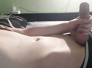 The guy jerks his dick lying on the bed