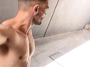 Handsome man walks naked on public parking garage and next to crowd...