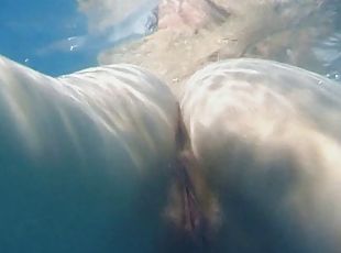 Skinny dipping teens play in the pool and finger underwater