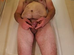 Obese hairy man plays with his dick while standing in bathtub befor...