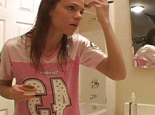 Young teen is doing make up in her bathroom using quite lots of det...